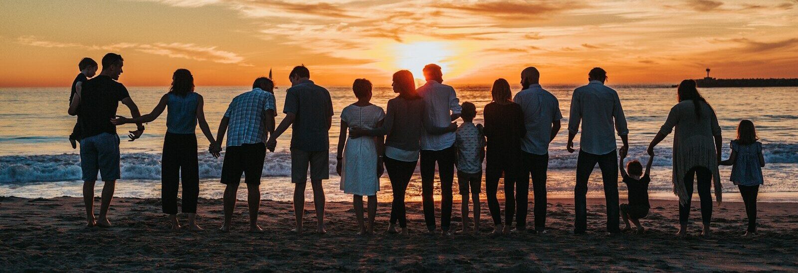 people standing on shore during golden hour